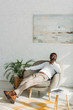 © LIGHTFIELD STUDIOS - stylish african american man resting in armchair and looking away