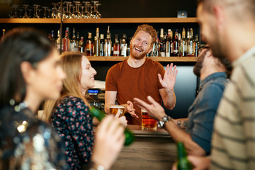 Poster - Handsome caucasian bartender giving beer on house to customers.