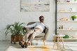 stylish african american man resting in armchair and looking away