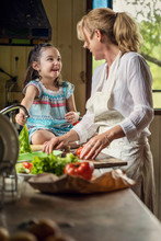 Grandmother And Granddaughter Preparing Food In Kitchen