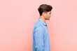 © kues1 - young handsome man on profile view looking to copy space ahead, thinking, imagining or daydreaming against pink background