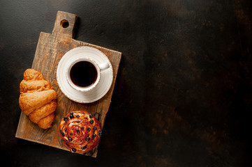 Coffee and croissant, bun on a stone table. morning breakfast, with copy space for text