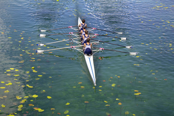 Men's quadruple rowing team on turquoise green lake