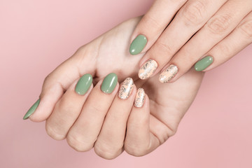 Closeup top view of beautiful hands of white woman isolated on pink pastel background. Fingernails with stylish trendy two colors faded manicure made with modern gel polish and silver stamping design.