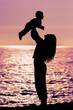 Silhouettes mom and baby at sunset. mother and little daughter play at sunset. Silhouette of mother throwing baby up on sunset