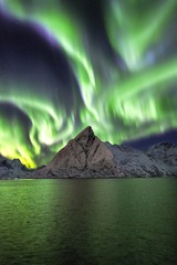vertical shot of the snow covered mountains under the beautiful northern lights in the sky