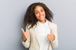 © Asier - Young african american business woman raising both thumbs up, smiling and confident.