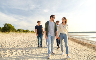 Wall Mural - friendship, leisure and people concept - group of happy friends walking along beach in summer