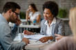 © Drazen - Happy African American financial advisor having consultations with clients in the office.