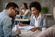 © Drazen - Black smiling insurance agent going through terms of the agreement with her client.