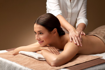 wellness, beauty and relaxation concept - beautiful young woman lying and having back massage at spa