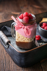 Wall Mural - No-bake layered dessert with dark chocolate mousse, crushed cookies and raspberry cream cheese in glass jar