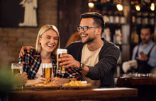 Cheerful Couple Toasting With Beer And Having Fun In A Pub.