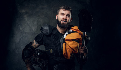 Portrait of serious bearded hockey player with his sport gear in hands.