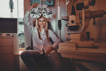 Wall Mural - Beautiful smiling woman is posing for photographer at oculist cabinet.