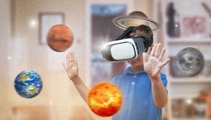 Boy with a virtual reality headset exploring planets in his room. The concept of using modern technologies for education.