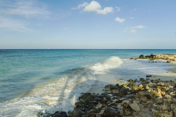 Big wave in Caribbean sea is breaking the coast. Turquoise sea water and blue sky. Great nature background.