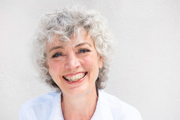 Close up portrait of smiling older woman by white background