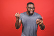 Photo of overjoyed black african american man knowing that he became winner of something so rejoicing enjoying news information while isolated over red background.