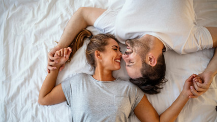 guy and a girl in a cozy home environment. happy man and woman lying in the bedroom stock photo. top