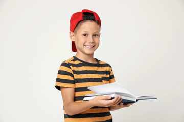 Wall Mural - Portrait of cute little boy reading book on grey background