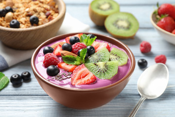 Delicious acai smoothie with chia seeds and fruits in dessert bowl served on white wooden table