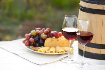 Composition with wine and snacks on white wooden table outdoors