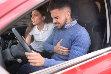 Young woman and man suffering from heart attack in car