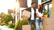 © New Africa - Happy couple with moving boxes and household stuff near their new house on sunny day