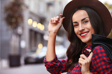 Wall Mural - Beautiful woman wearing hat in city on autumn day