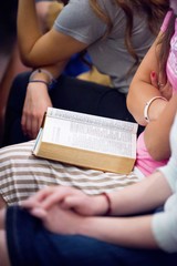 Vertical shot of a group of people sitting in the church and reading the Bible