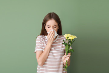 Wall Mural - Young woman suffering from allergy to flowers on color background