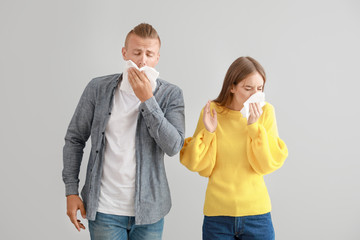 Wall Mural - Young couple suffering from allergy on light background