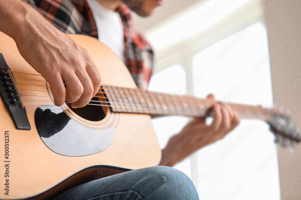 Handsome man playing guitar at home, closeup