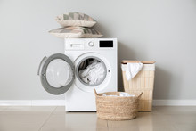 Modern Washing Machine With Laundry Near White Wall