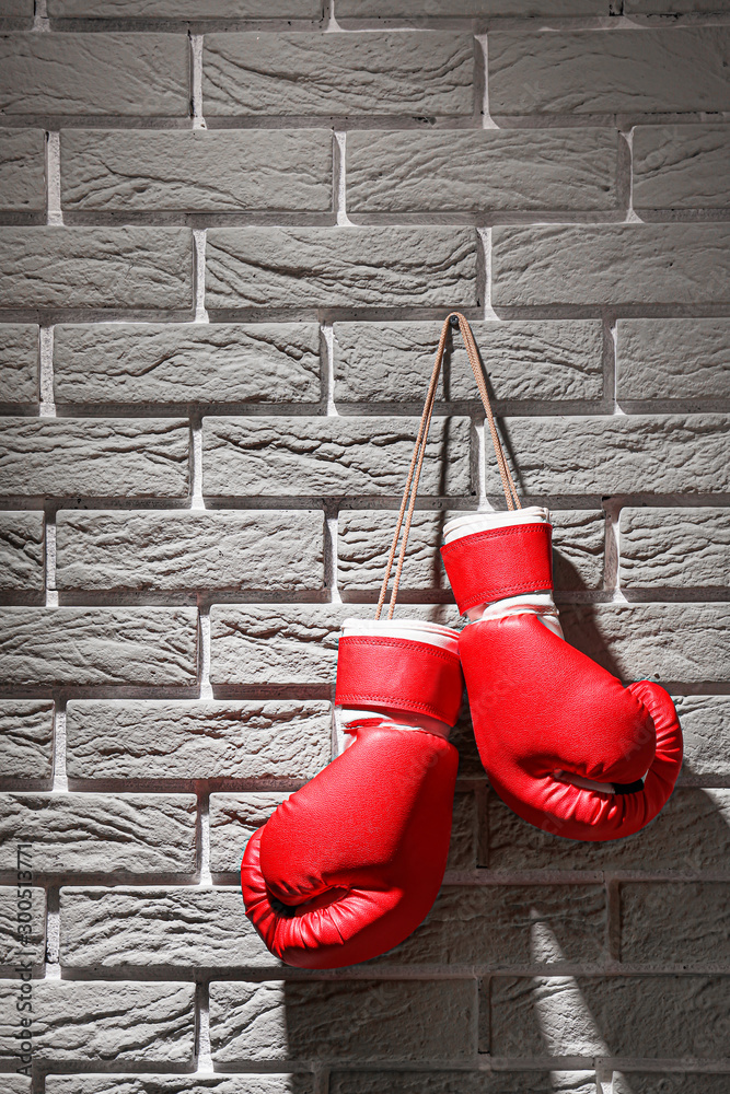 Pair of boxing gloves hanging on brick wall