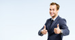 © vgstudio - Portrait of happy businessman showing thumbs up gesture, isolated over grey background. Business success concept picture. Copy space for some text or advertise slogan.