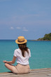 © allenkayaa - Young woman in a hat sits on a pier near the clear turquoise sea
