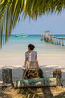 © allenkayaa - A young woman under a palm tree on the shore of the Gulf of Thailand. Woman in a hat looks at the sea