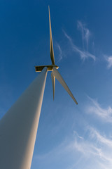 Vertical shot looking up at a wind turbine, blue sky and white clouds.  Environmental concept