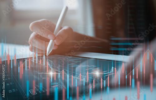 Fotografía Stock exchange market concept, businessman trader looking on tablet with graphs analysis candle line in office room, diagrams on screen