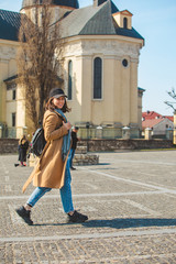 Wall Mural - young pretty fashionable woman walking in brown coat by street