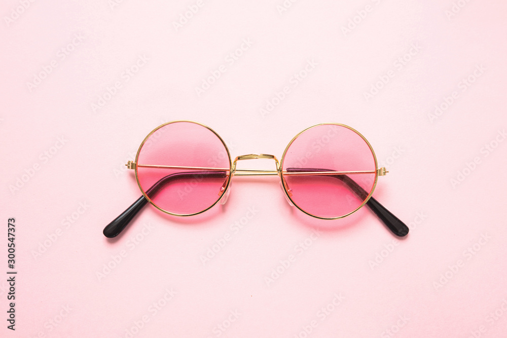 Golden frame sunglasses with pink lens on pink background, top view - obrazy, fototapety, plakaty 
