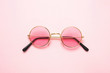 Leinwandbild Motiv Golden frame sunglasses with pink lens on pink background, top view