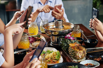 Poster - Hands of party guests sitting at dinner table with traditional Asian cuisine and texting friends of checking social media on smartphones