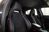 Fototapeta Do pokoju - Close-up on the front sport car seats with black leather trim, lateral support and fabric inserts, of used vehicle in after detailing and dry cleaning. Auto service industry.