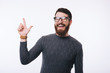 © Vulp - Amazed handsome man with beard wearing eyeglasses and pointing away at copyspace