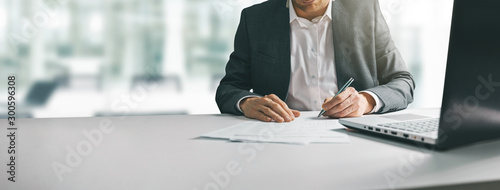 Cuadros en Lienzo young man in suit writing business papers at desk in modern coworking office