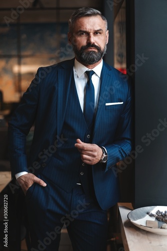 Cuadros en Lienzo Stylish bearded man in a suit standing in modern office