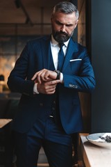 Wall Mural - Stylish bearded man in a suit standing in modern office